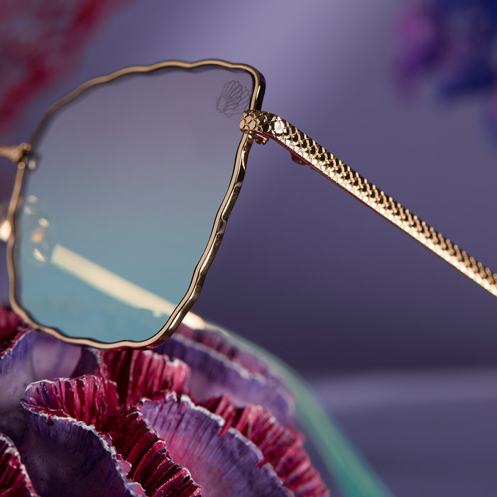 lifestyle - disney princess x diff eyewear featuring the ariel 2.0 sunglasses with a Shimmering Gold frame and Iridescent Sea Foam Pink To Blue Gradient Lenses detailed view