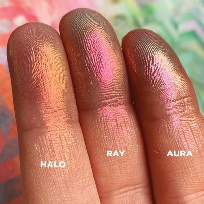Left angled finger swatches on fair skin tone of Aura Iridescent Multichrome Eyeshadow shifts compared to Halo, Ray