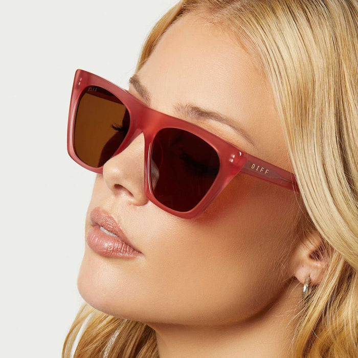 on model - female wearing diff eyewear featuring the avril cat eye oversized sunglasses with a guava pink frame and brown lenses angled view