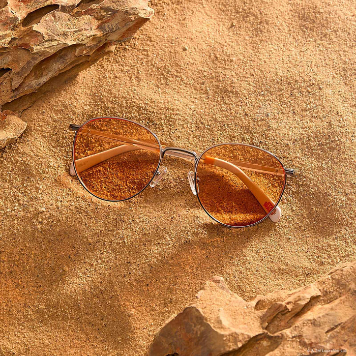 lifestyle - laying on sand star wars x diff eyewear featuring the bb-8™ round sunglasses with a droid white with silver frame and orange lenses