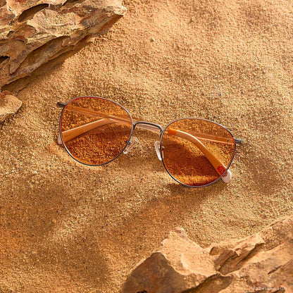 lifestyle - laying on sand star wars x diff eyewear featuring the bb-8™ round sunglasses with a droid white with silver frame and orange lenses