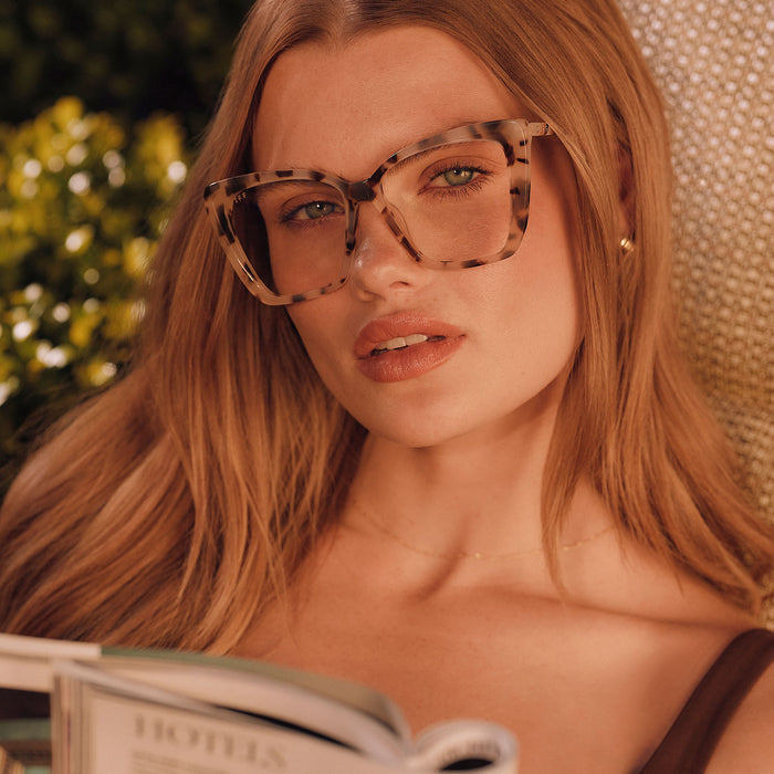 lifestyle - female lounging outside wearing diff eyewear becky ii cat eye glasses with a cream tortoise frame