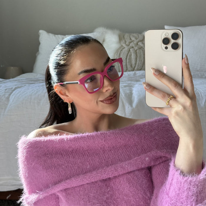 lifestyle - Emily Gordon Brunette influencer wearing light pink fuzzy off the should sweater with bright pink blue light glasses from diff eyewear