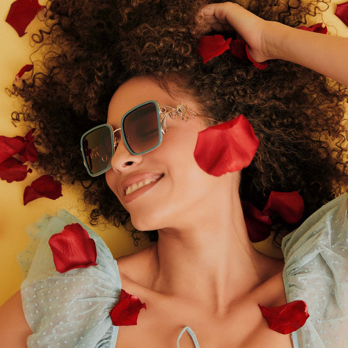on model - female wearing disney princess x diff eyewear featuring the belle 2.0 oversized square sunglasses with a gold and enchanting blue frame with brown gradient polarized lenses angled view