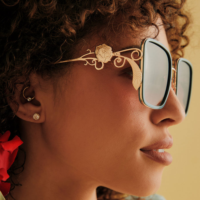 on model - female wearing disney princess x diff eyewear featuring the belle 2.0 oversized square sunglasses with a gold and enchanting blue frame with brown gradient polarized lenses detailed view of temple rose design