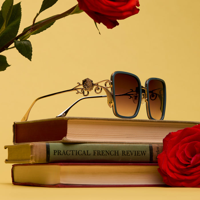 lifestyle - flat lay of disney princess x diff eyewear featuring the belle 2.0 oversized square sunglasses with a gold and enchanting blue frame with brown gradient polarized lenses