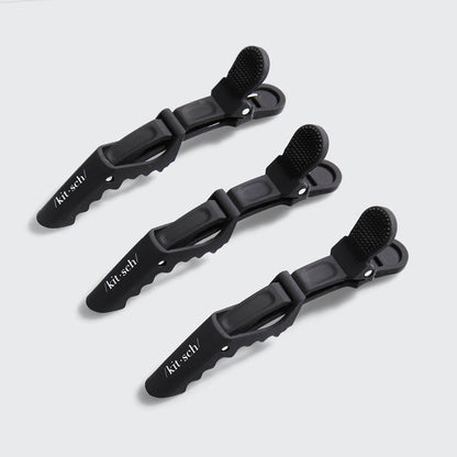 Three black no-slip alligator hair clips arranged on a gray background.