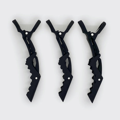 Three black alligator clips shown sideways to display the no-slip teeth and hinged design.