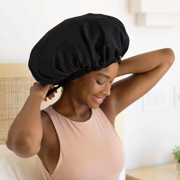 Model wearing KITSCH Black XL Adjustable Satin Bonnet — lifestyle shot — worn while sleeping to protect hair overnight