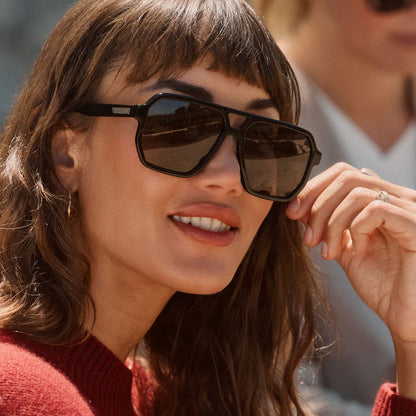 lifestyle - female wearing diff eyewear featuring the cameron navigator sunglasses with a black frame and grey polarized lenses angled view