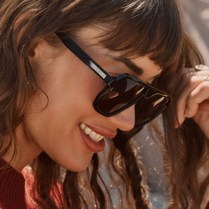 lifestyle - female wearing diff eyewear featuring the cameron navigator sunglasses with a black frame and grey polarized lenses side view