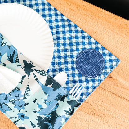 Blue and white checkered placemat with floral patterns on a wooden surface
