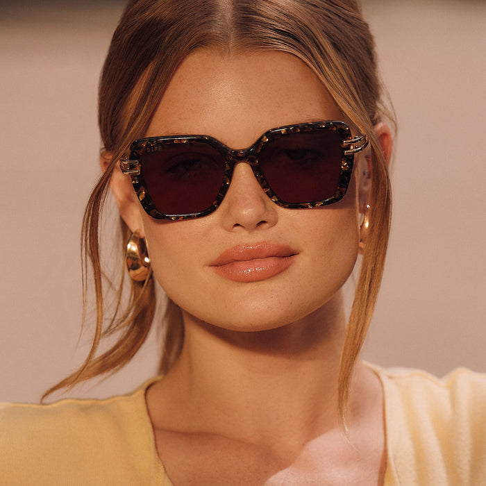 lifestyle - female wearing diff eyewear featuring the dasha square sunglasses with a glitter gold tortoise frame and brown lenses front view