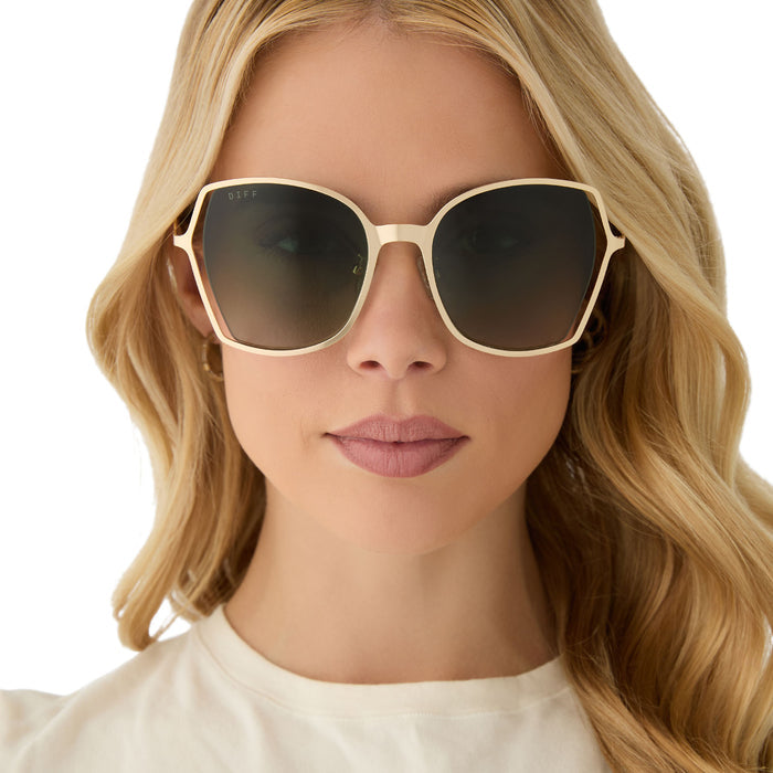 on model - female wearing diff eyewear featuring the donna iii square sunglasses with a gold frame and cool matcha gradient polarized lenses front view