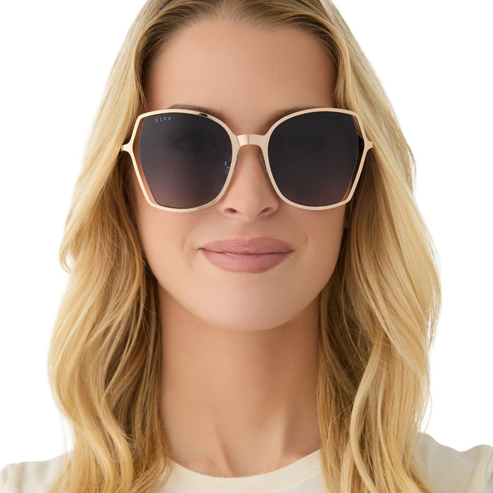 on model - female wearing diff eyewear featuring the donna iii square sunglasses with a gold frame and midnight blue gradient polarized lenses front view