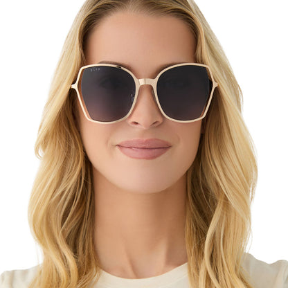 on model - female wearing diff eyewear featuring the donna iii square sunglasses with a gold frame and midnight blue gradient polarized lenses front view