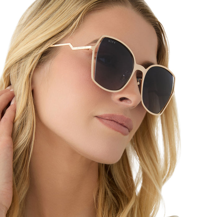 on model - female wearing diff eyewear featuring the donna iii square sunglasses with a gold frame and midnight blue gradient polarized lenses side view