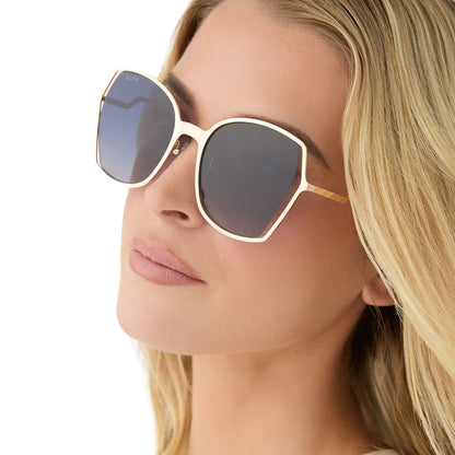 on model - female wearing diff eyewear featuring the donna iii square sunglasses with a gold frame and midnight blue gradient polarized lenses angled view