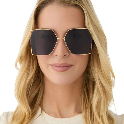 on model - female wearing diff eyewear featuring the donna iv square sunglasses with a gold frame and midnight blue polarized lenses front view