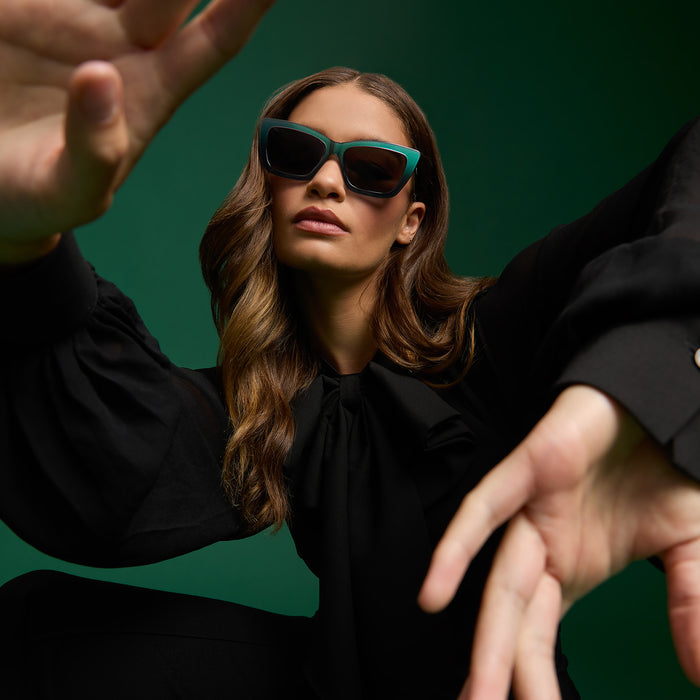 lifestyle - female wearing wicked x diff eyewear featuring the elphaba emerald square sunglasses with a black green gradient frame and grey lenses front view