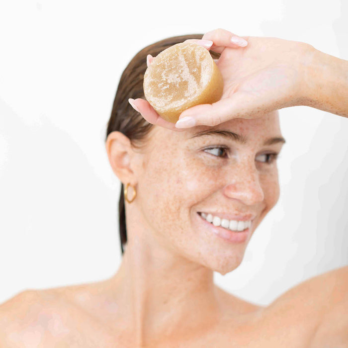 Model holding the Kitsch Sugar Solid Body Scrub Bar after use, showcasing the bottle-free exfoliating body scrub bar.