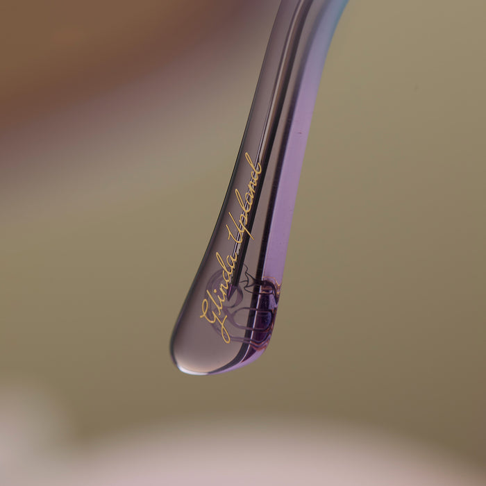 lifestyle - wicked x diff eyewear featuring the glinda upland butterfly cat eye sunglasses with a blue pink gradient frame and blue to pink lenses detailed view of temple tip with glinda upland's name