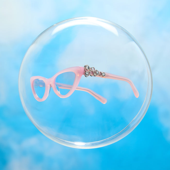 lifestyle - wicked x diff eyewear featuring the glinda upland for good cat eye sunglasses with a pink frame and pink lenses floating in a bubble