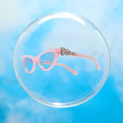 lifestyle - wicked x diff eyewear featuring the glinda upland for good cat eye sunglasses with a pink frame and pink lenses floating in a bubble