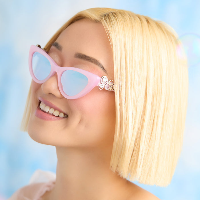 lifestyle - female wearing wicked x diff eyewear featuring the glinda upland for good cat eye sunglasses with a pink frame and pink lenses side view