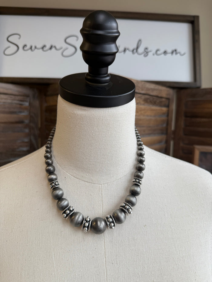 Graduated pearl necklace with dark gray beads and silver-tone accents on mannequin