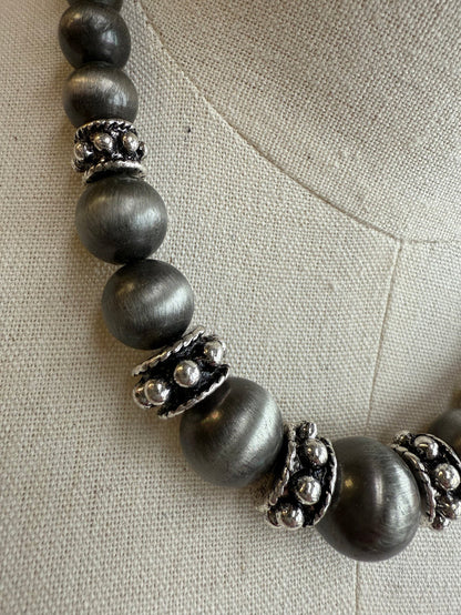 Graduated pearl necklace with dark gray beads and silver-tone filigree spacers