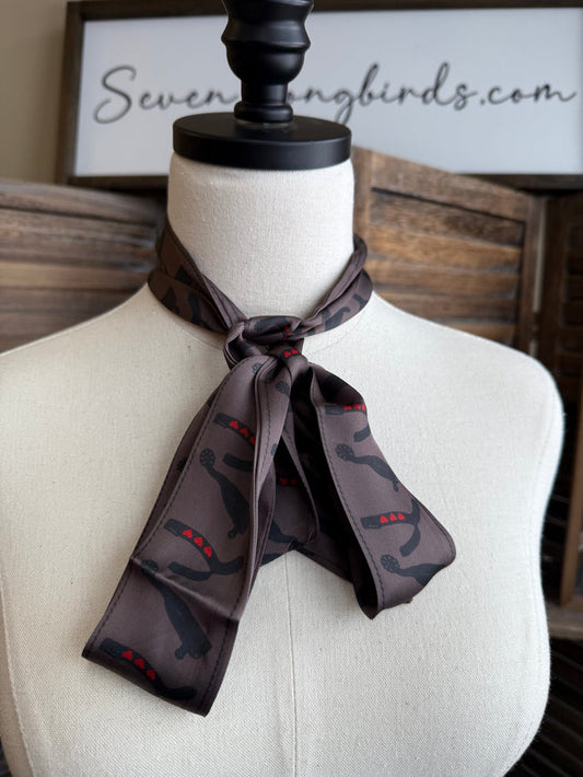 Twilly scarf tied in a bow on a mannequin, dark fabric with horseshoe and red heart print