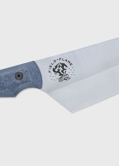 Close-up of a knife with a blue handle and "Field Flame" logo on the blade, featuring a campfire illustration.