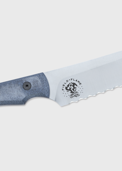 Close-up of a serrated knife blade with a blue handle, featuring the "Field & Flame" logo on a light gray background.