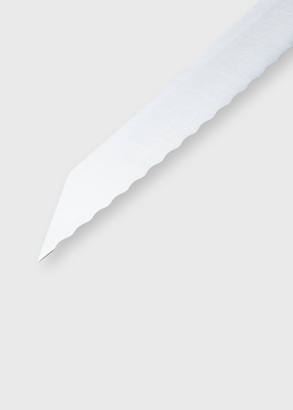 Close-up of a serrated knife blade on a light gray background, showcasing its sharp, jagged edge and metallic sheen.