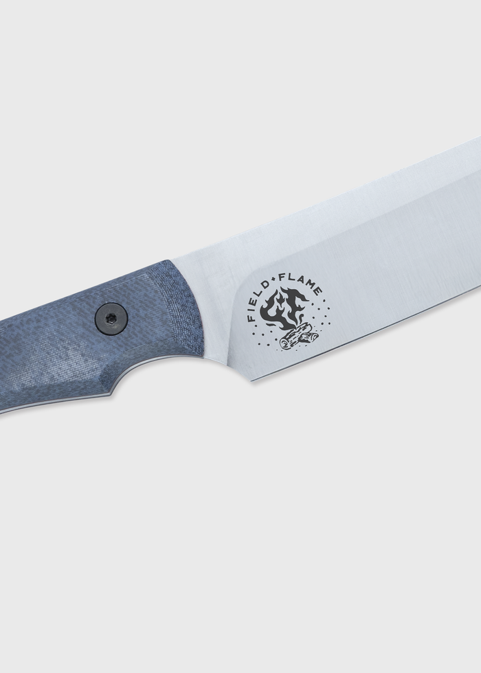 Close-up of a knife with a blue handle and "Field + Flame" logo on the blade, set against a plain background.