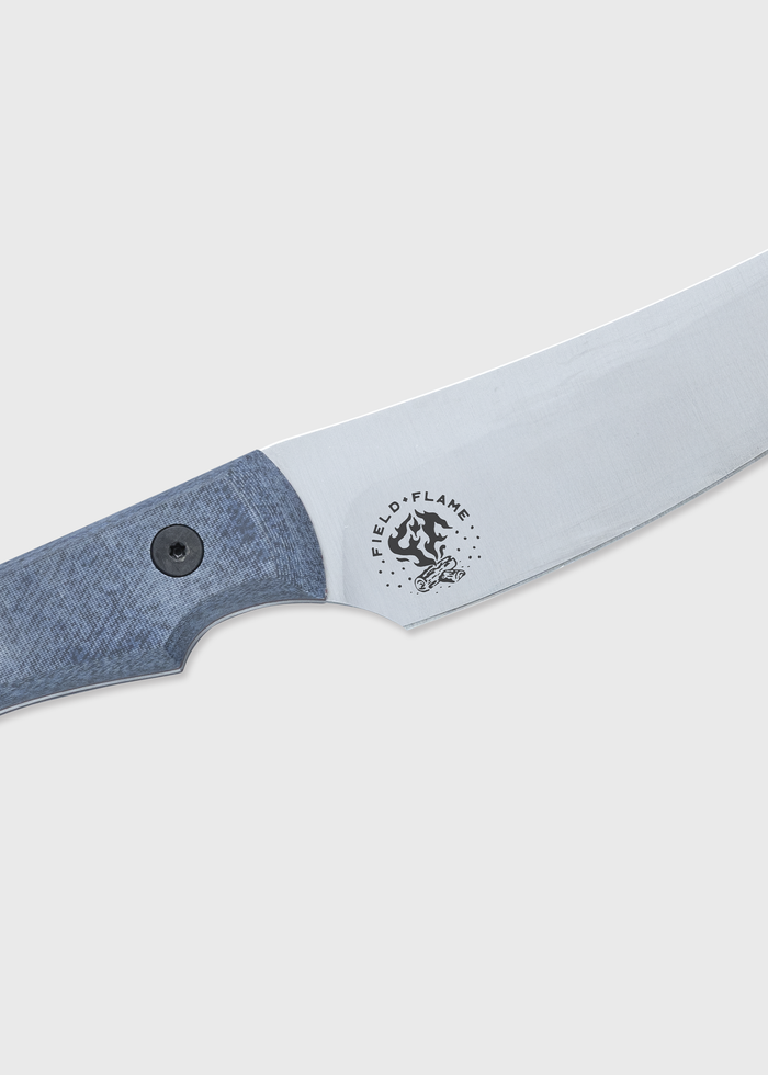 Close-up of a knife with a textured blue handle and "Field & Flame" logo on the blade, set against a light gray background.