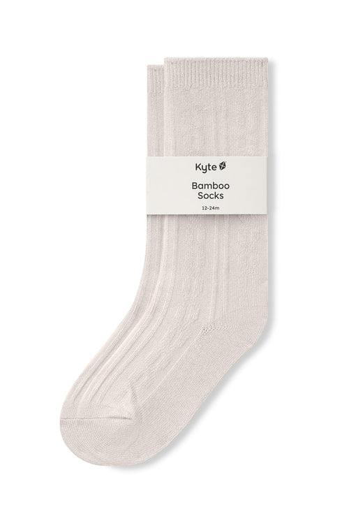 Knee high socks in oat laying flat on a white background.