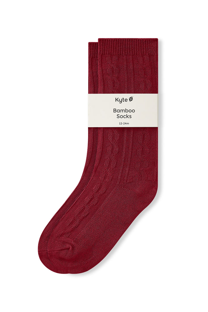 Knee high socks in ruby laying flat on a white background.