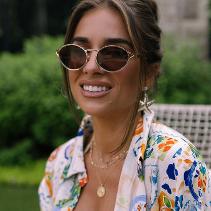 lifestyle - jessie james decker female  wearing diff eyewear limoncello oval sunglasses with a gold frame and brown lenses front view