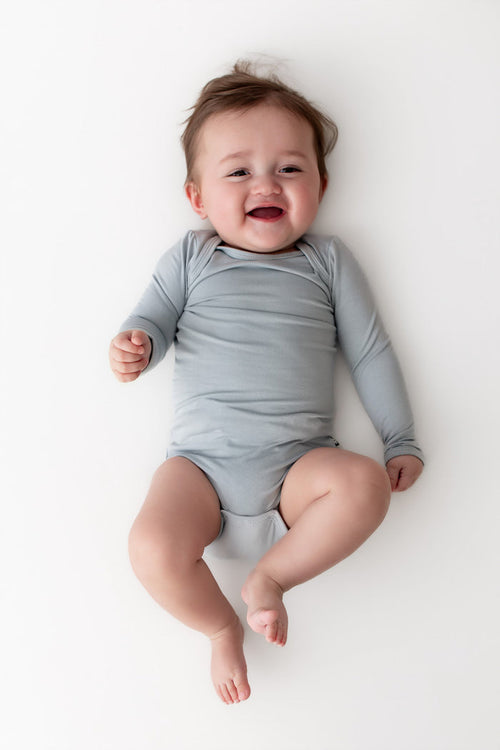 Baby wearing a light blue onesie on a white background