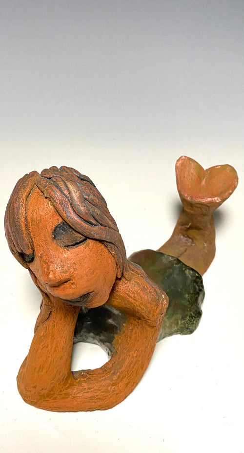Marie waits patiently! Marie stands 6" x 3.5" x 7.5" and weighs 1.11 lbs. Marie has a lovely honey brown complexion with ruby red lips.. Her long loving arms are underneath her face as she ponders. Marie dress is a copper glazed and she has hair made of clay. Marie is bright eyed and ready to be placed in a good home.