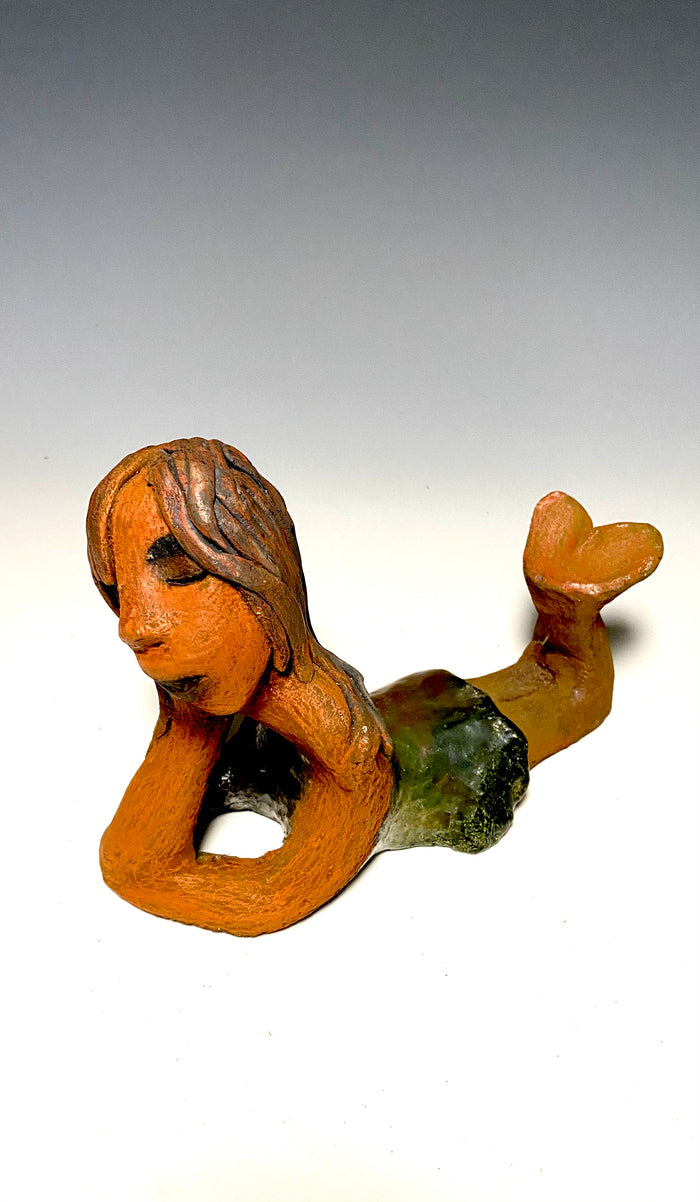 Marie waits patiently! Marie stands 6" x 3.5" x 7.5" and weighs 1.11 lbs. Marie has a lovely honey brown complexion with ruby red lips.. Her long loving arms are underneath her face as she ponders. Marie dress is a copper glazed and she has hair made of clay. Marie is bright eyed and ready to be placed in a good home.