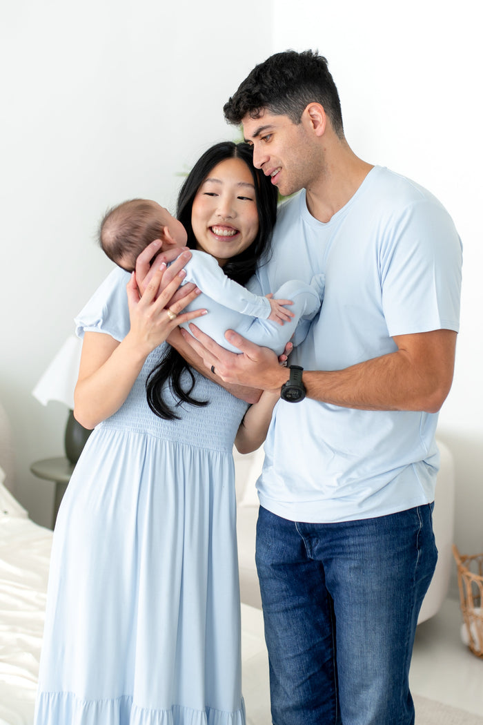 Family of 3, mom and dad and baby, wearing matching light blue outfits