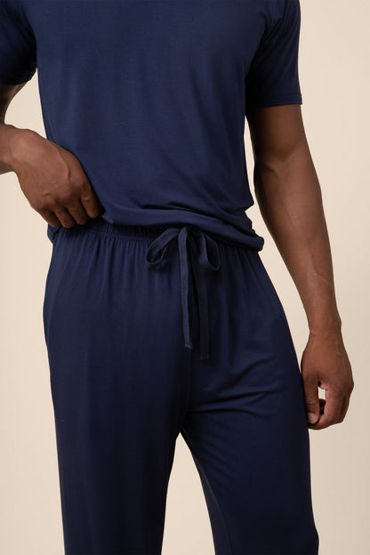 Person wearing navy blue pajama set on a beige background