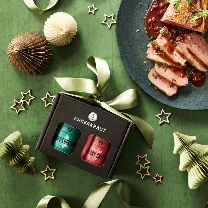 Merry Christmas Gewürz-Box aus schwarzem Karton neben weihnachtlicher Deko und einem Teller Gänsebraten.