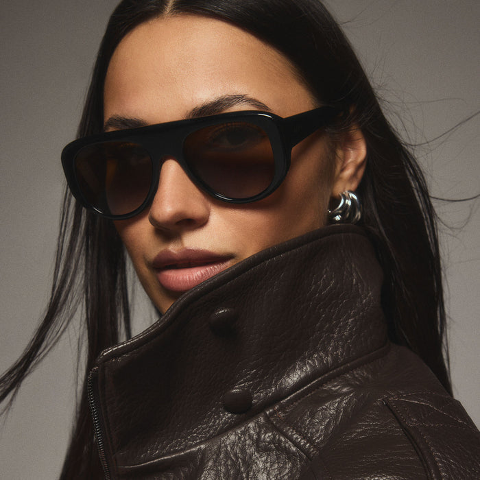 on model - female wearing diff eyewear featuring the morgan shield sunglasses with a black frame and brown lenses angled view from the DIFFine campaign