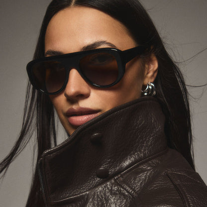 on model - female wearing diff eyewear featuring the morgan shield sunglasses with a black frame and brown lenses angled view from the DIFFine campaign