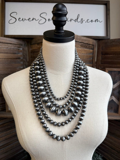 Multi-strand graduated metallic gray pearl necklace on mannequin, V-shaped layered rows
