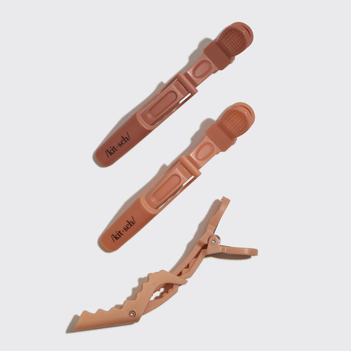 Three multicolor no-slip alligator hair clips in neutral terracotta shades on a gray background.